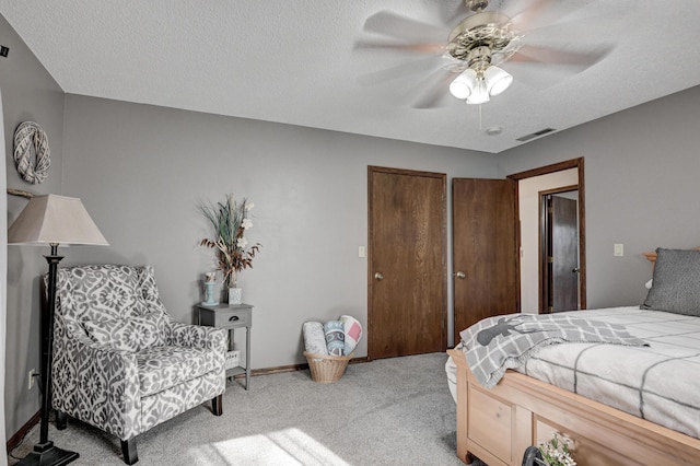 bedroom featuring light carpet, a textured ceiling, ceiling fan, and multiple closets