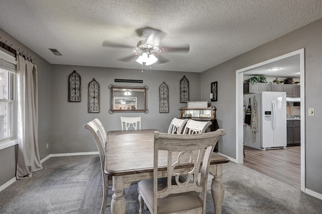 dining area featuring ceiling fan, wood-type flooring, and a textured ceiling