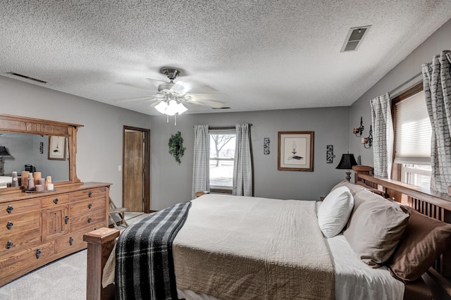 bedroom with ceiling fan, carpet floors, and a textured ceiling