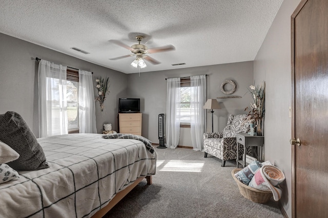 bedroom with multiple windows, ceiling fan, light colored carpet, and a textured ceiling