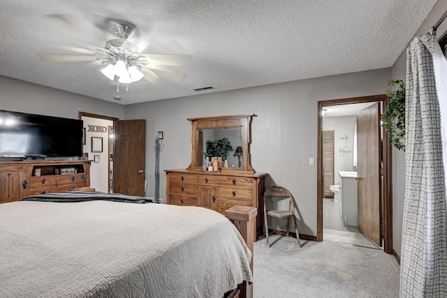 carpeted bedroom with ensuite bath, ceiling fan, and a textured ceiling