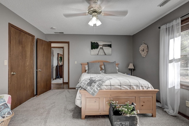 bedroom with light carpet, a textured ceiling, and ceiling fan