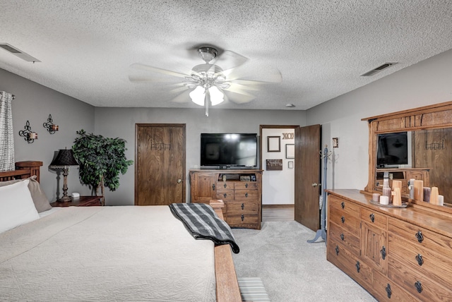 bedroom with a textured ceiling, ceiling fan, and light carpet