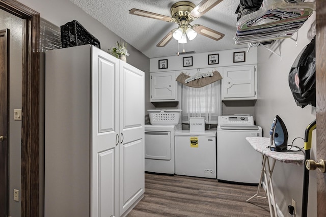 clothes washing area featuring cabinets, dark hardwood / wood-style floors, ceiling fan, washing machine and dryer, and a textured ceiling