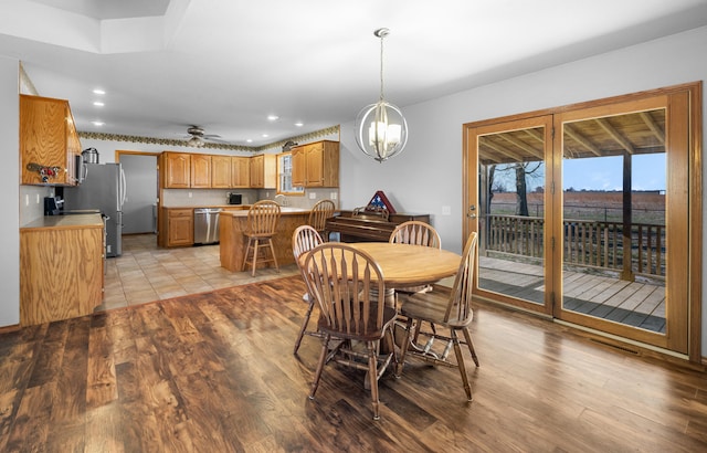 dining room featuring ceiling fan with notable chandelier and light hardwood / wood-style flooring