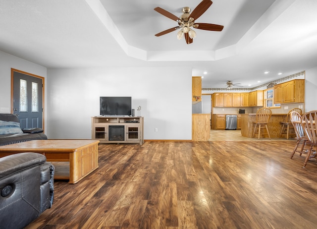 living room with hardwood / wood-style flooring, ceiling fan, and a tray ceiling