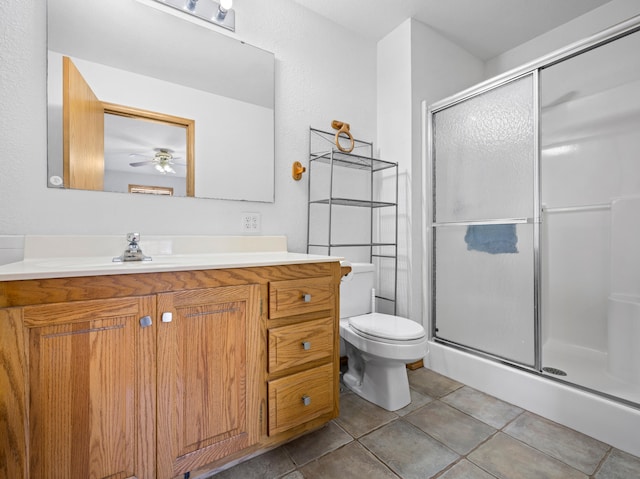 bathroom with ceiling fan, tile patterned flooring, toilet, vanity, and a shower with shower door