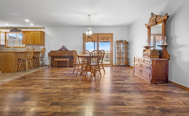 dining space featuring a healthy amount of sunlight, dark hardwood / wood-style flooring, and an inviting chandelier