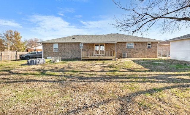 back of property with central AC, a wooden deck, and a lawn