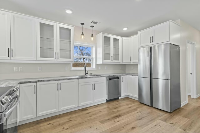 kitchen with white cabinets, sink, hanging light fixtures, light hardwood / wood-style floors, and stainless steel appliances