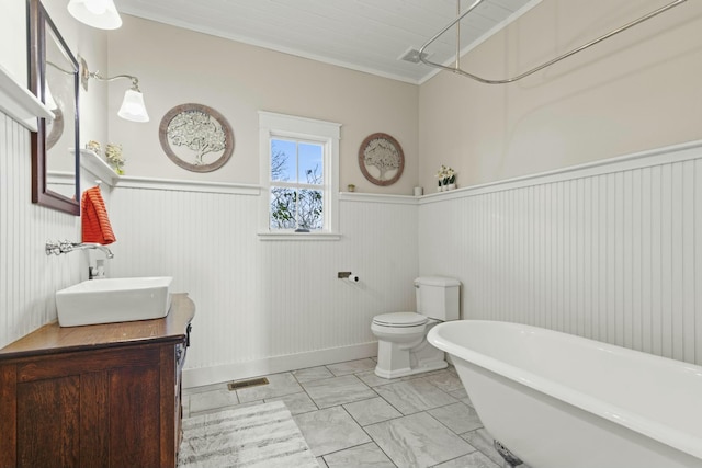 bathroom with vanity, a tub to relax in, toilet, and ornamental molding