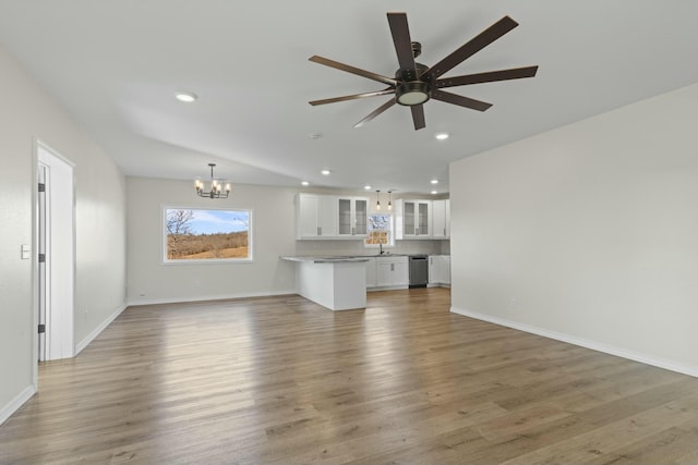 unfurnished living room with ceiling fan with notable chandelier, hardwood / wood-style flooring, and sink