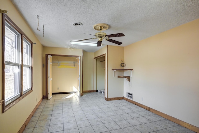 empty room with light tile patterned floors, a textured ceiling, and ceiling fan