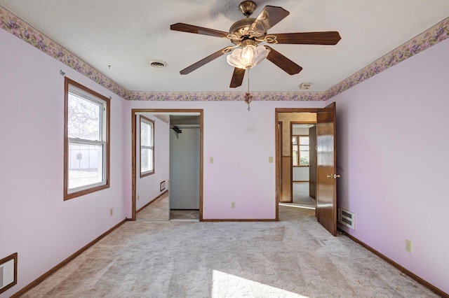 unfurnished bedroom featuring a closet, a textured ceiling, light colored carpet, and ceiling fan