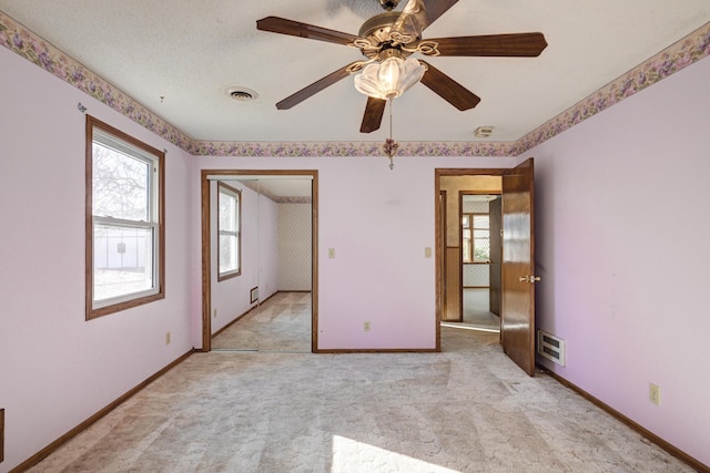 unfurnished room with ceiling fan, light colored carpet, and a textured ceiling