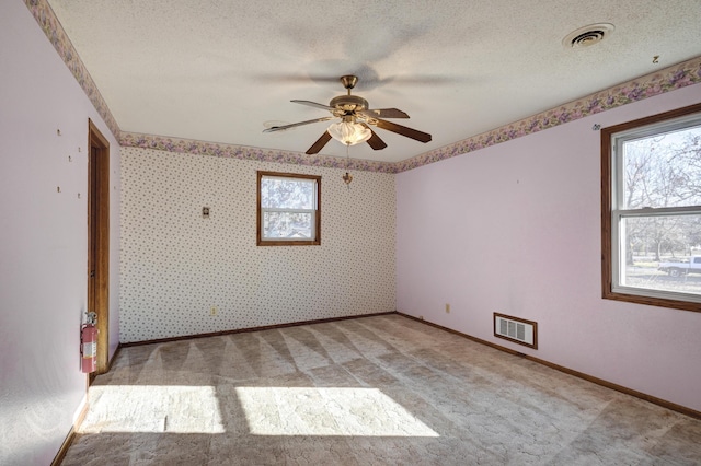 carpeted empty room featuring ceiling fan and a textured ceiling