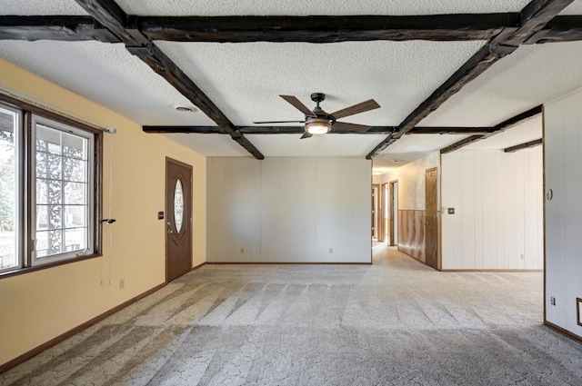 unfurnished room featuring beam ceiling, ceiling fan, light carpet, and a textured ceiling