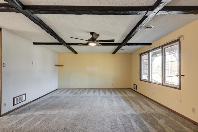 unfurnished room with beamed ceiling, ceiling fan, carpet floors, and a textured ceiling