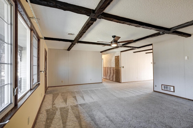 empty room with coffered ceiling, ceiling fan, a textured ceiling, beamed ceiling, and light colored carpet