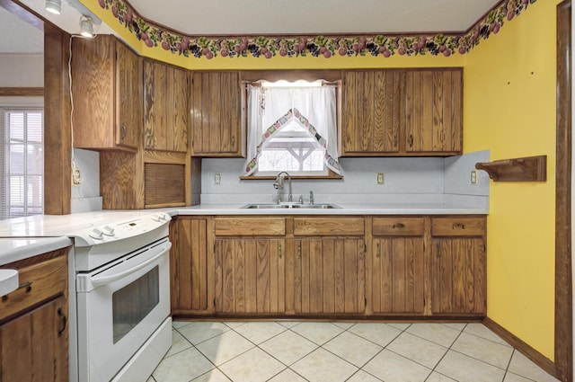 kitchen featuring light tile patterned flooring, a textured ceiling, white electric stove, and sink