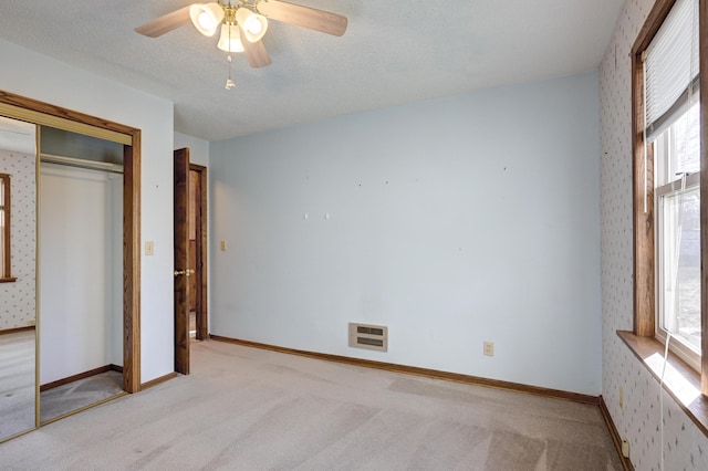 unfurnished bedroom featuring multiple windows, ceiling fan, a closet, and a textured ceiling