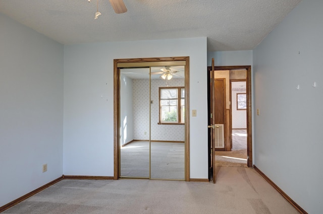 unfurnished bedroom featuring ceiling fan, a textured ceiling, light carpet, and a closet