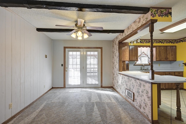 kitchen featuring beamed ceiling, a breakfast bar, kitchen peninsula, and a wealth of natural light