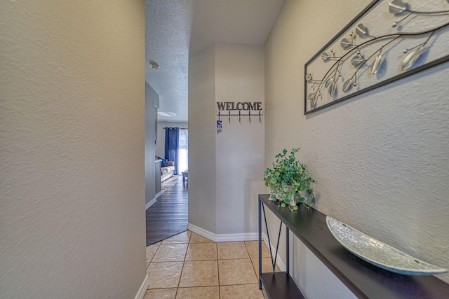 hall with a textured ceiling and light hardwood / wood-style flooring