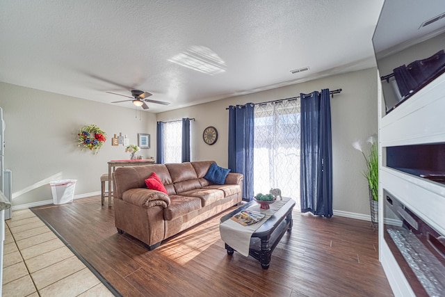 living room featuring ceiling fan, wood-type flooring, and a textured ceiling