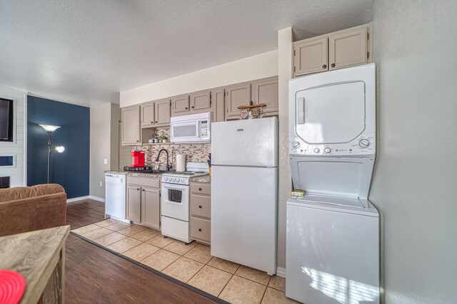 29 Fall Creek Dr Unit 2, Branson, MO 65616 - kitchen featuring white appliances, stacked washer and clothes dryer, a textured ceiling, light wood finished floors, and backsplash