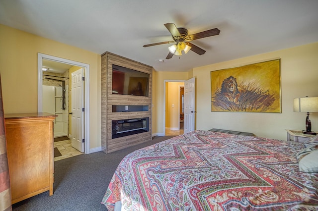 carpeted bedroom with ceiling fan, a large fireplace, and ensuite bath