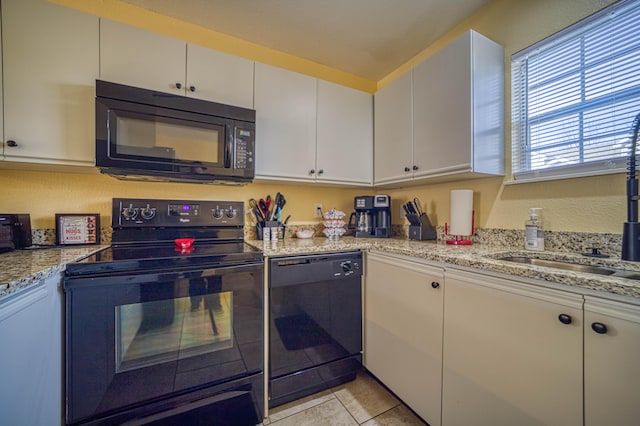 kitchen with light stone countertops, light tile patterned floors, white cabinetry, and black appliances