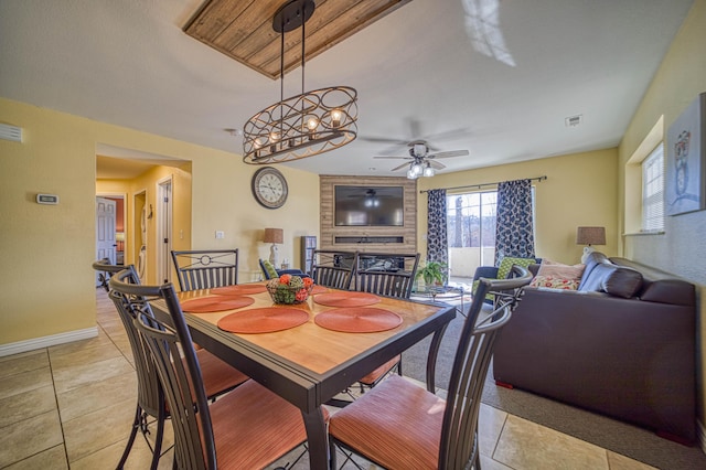 tiled dining area featuring ceiling fan and a fireplace