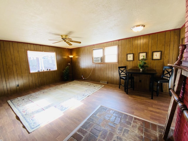 interior space with ceiling fan, dark hardwood / wood-style flooring, wood walls, cooling unit, and a textured ceiling