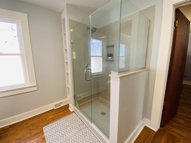 bathroom with a shower with door, wood-type flooring, and toilet