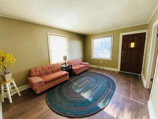 living room featuring a textured ceiling, ornamental molding, and dark wood-type flooring