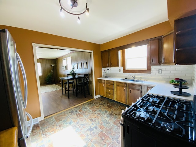 kitchen with stainless steel fridge, tasteful backsplash, sink, hardwood / wood-style flooring, and black gas stove