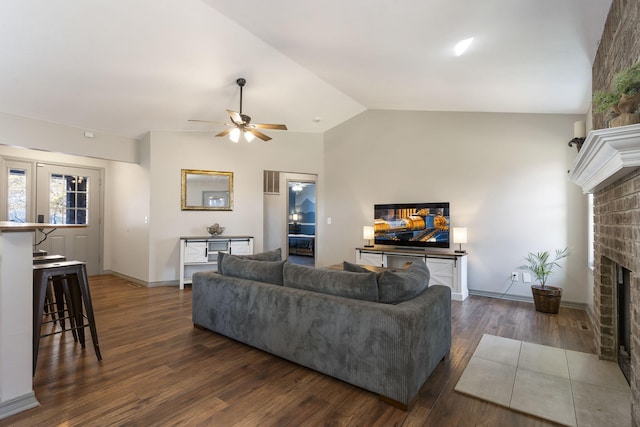 living room featuring a fireplace, dark hardwood / wood-style flooring, vaulted ceiling, and ceiling fan