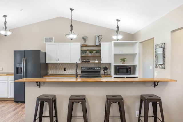 kitchen featuring wood counters, a kitchen bar, vaulted ceiling, electric range, and white cabinetry