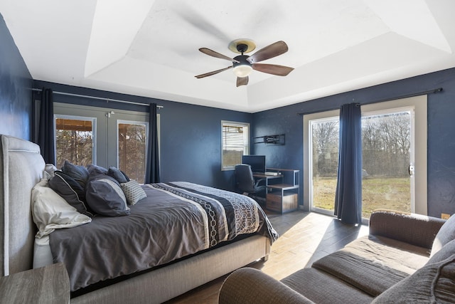 bedroom with a tray ceiling, multiple windows, and ceiling fan