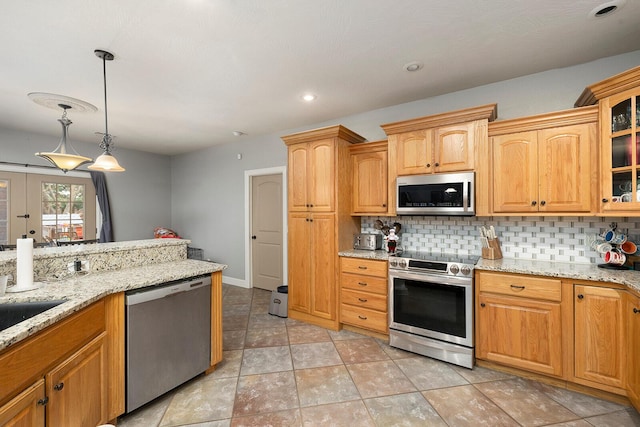 kitchen featuring light stone countertops, french doors, stainless steel appliances, pendant lighting, and decorative backsplash