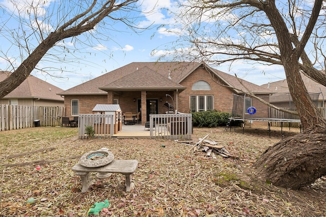 rear view of property featuring a patio area and a trampoline