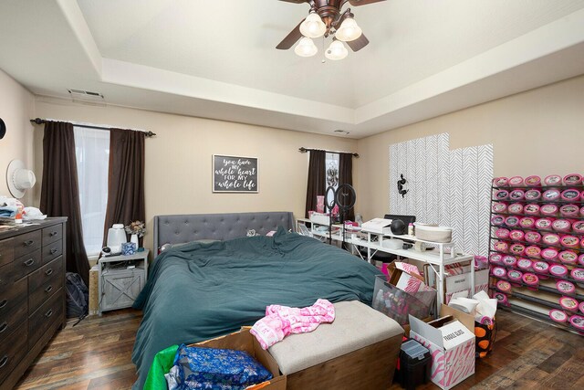 bedroom featuring a tray ceiling, ceiling fan, and dark wood-type flooring