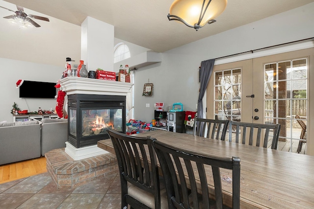 dining room with hardwood / wood-style flooring, ceiling fan, a multi sided fireplace, and french doors