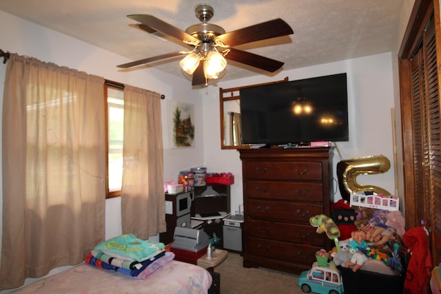 bedroom featuring carpet, ceiling fan, and a textured ceiling