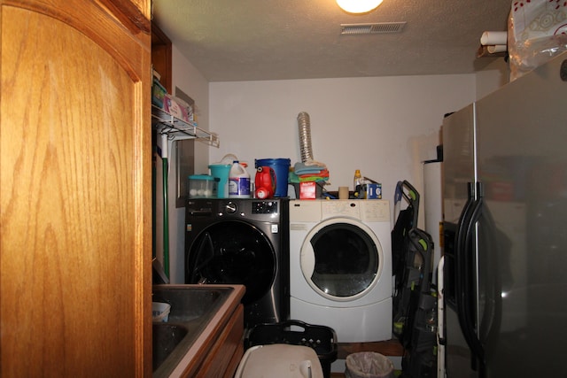 laundry room with washing machine and dryer, sink, and a textured ceiling