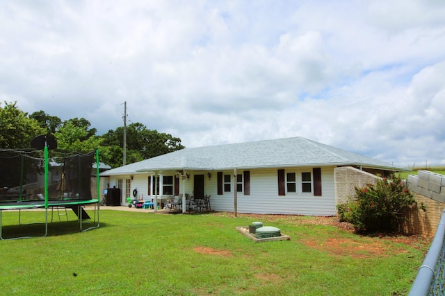 back of house featuring a lawn, ceiling fan, a patio area, and a trampoline