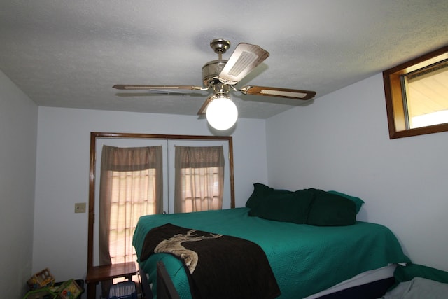 bedroom featuring ceiling fan, a textured ceiling, and multiple windows