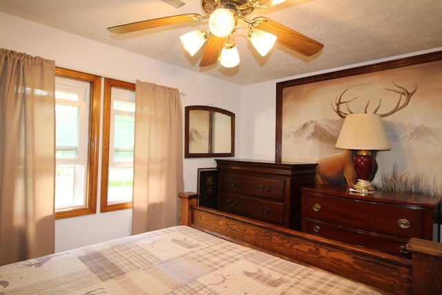 bedroom with ceiling fan and a textured ceiling