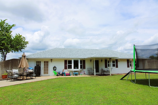 rear view of house with a patio area, a yard, and a trampoline